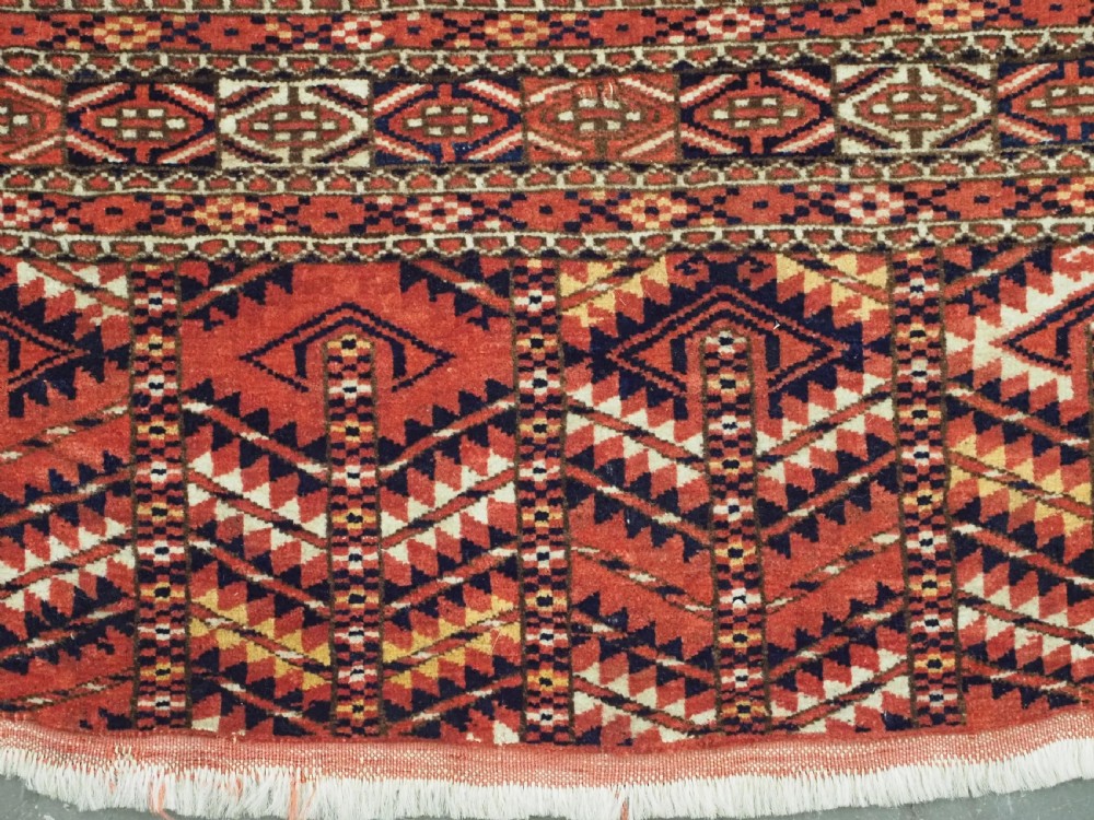 An antique Tekke Turkmen chuval bag face featuring repeating geometric gul motifs on a rust red wool pile with a detailed elem skirt border. View IX