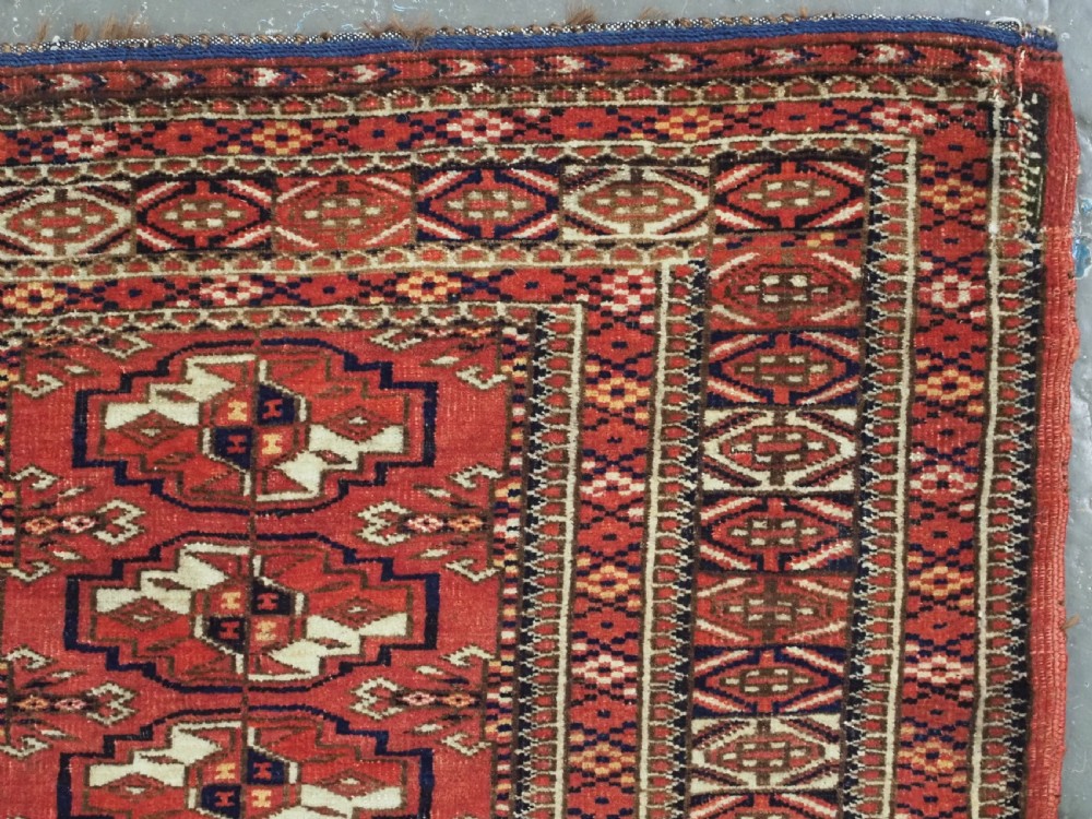 An antique Tekke Turkmen chuval bag face featuring repeating geometric gul motifs on a rust red wool pile with a detailed elem skirt border. View X