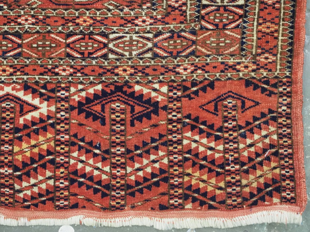 An antique Tekke Turkmen chuval bag face featuring repeating geometric gul motifs on a rust red wool pile with a detailed elem skirt border. View XI