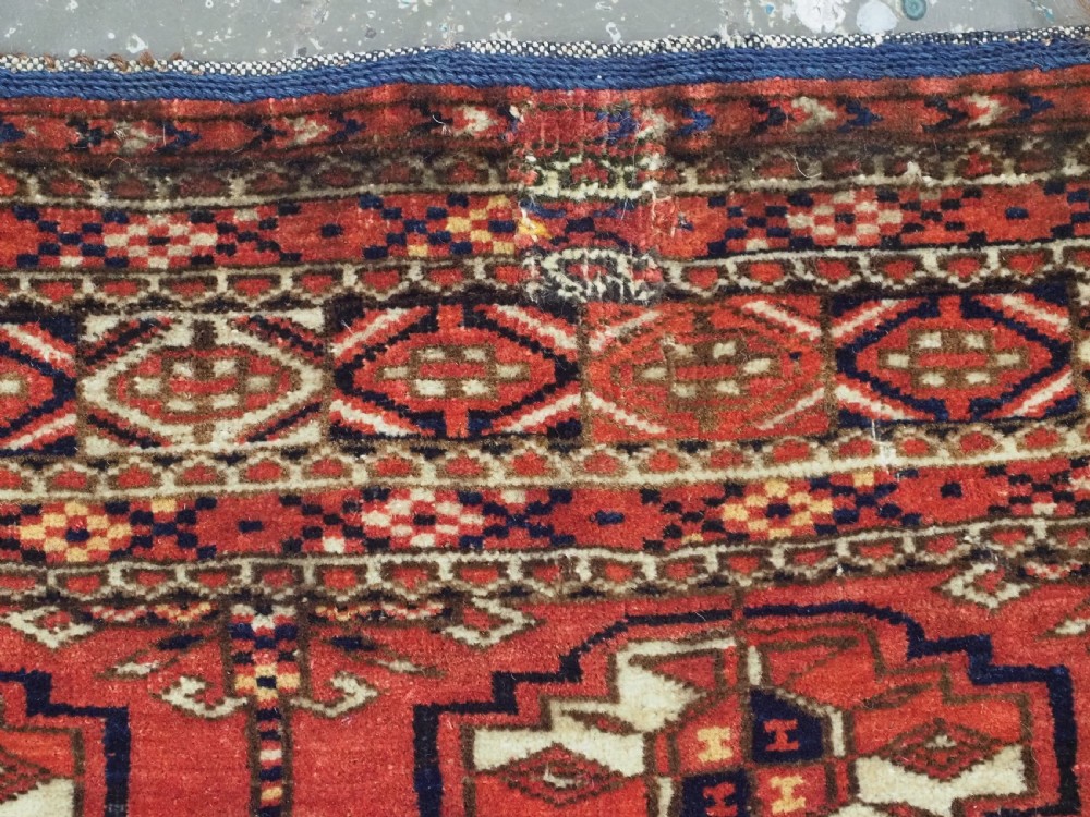 An antique Tekke Turkmen chuval bag face featuring repeating geometric gul motifs on a rust red wool pile with a detailed elem skirt border. View XII