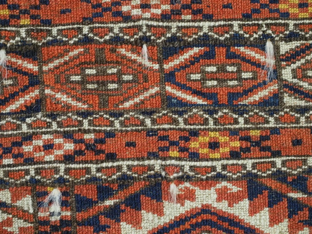 An antique Tekke Turkmen chuval bag face featuring repeating geometric gul motifs on a rust red wool pile with a detailed elem skirt border. View XIII