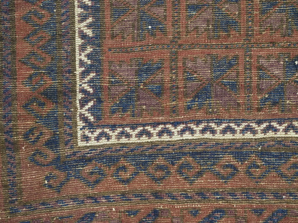 An antique hand-knotted Baluch wool prayer rug featuring a central mihrab arch motif with repeat geometric lotus leaf patterns in deep red, navy blue, and white. View XI