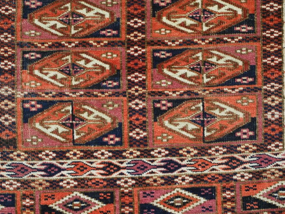 A hand-knotted wool Tekke Turkmen chuval face with repeating geometric aina gul motifs in red, navy blue, and ivory tones, finished with a fringed lower border. View VIII