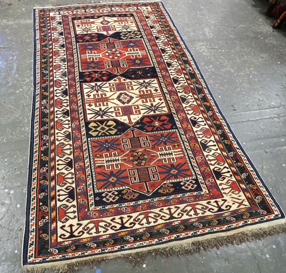 An antique hand-knotted Caucasian Shirvan wool rug featuring geometric stepped medallions on a deep blue field with red and cream patterned borders. View II