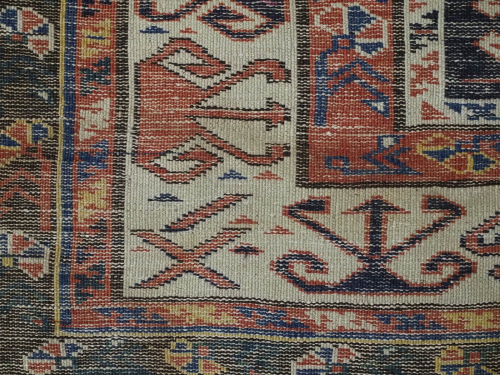 An antique hand-knotted Caucasian Shirvan wool rug featuring geometric stepped medallions on a deep blue field with red and cream patterned borders. View XIV