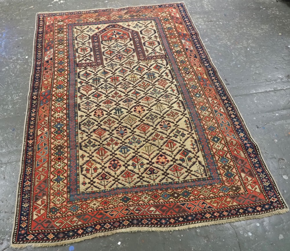 An antique Caucasian Shirvan prayer rug featuring an ivory ground decorated with a geometric floral lattice pattern and a arched mihrab. View II