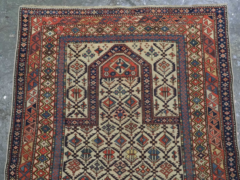 An antique Caucasian Shirvan prayer rug featuring an ivory ground decorated with a geometric floral lattice pattern and a arched mihrab. View III