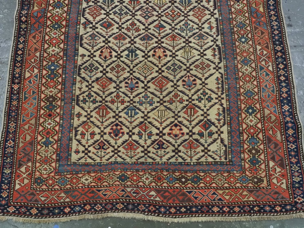An antique Caucasian Shirvan prayer rug featuring an ivory ground decorated with a geometric floral lattice pattern and a arched mihrab. View V