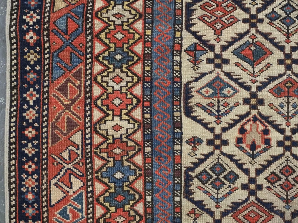 An antique Caucasian Shirvan prayer rug featuring an ivory ground decorated with a geometric floral lattice pattern and a arched mihrab. View VII