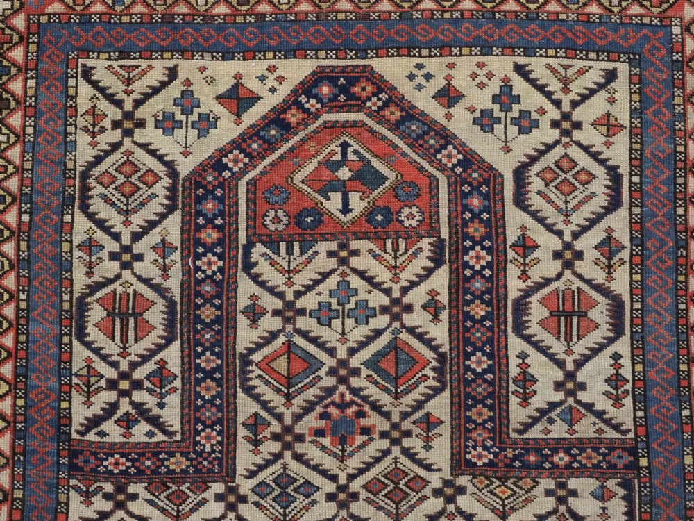 An antique Caucasian Shirvan prayer rug featuring an ivory ground decorated with a geometric floral lattice pattern and a arched mihrab. View VIII
