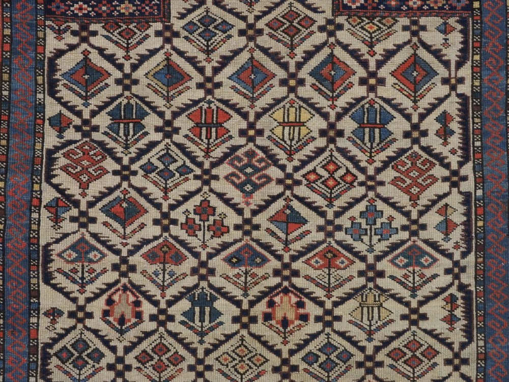 An antique Caucasian Shirvan prayer rug featuring an ivory ground decorated with a geometric floral lattice pattern and a arched mihrab. View IX