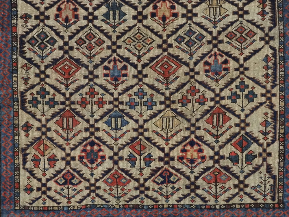 An antique Caucasian Shirvan prayer rug featuring an ivory ground decorated with a geometric floral lattice pattern and a arched mihrab. View X