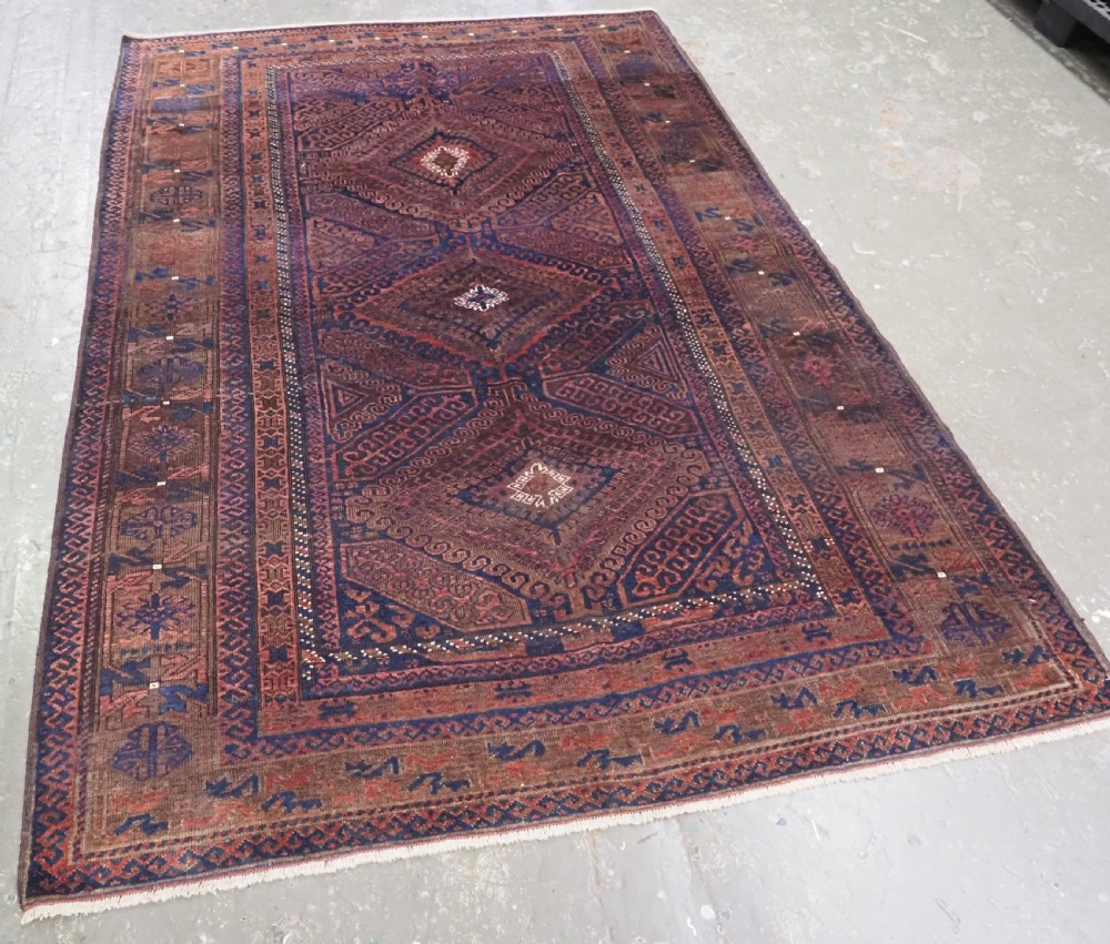 An antique hand-knotted wool carpet featuring dark brown and indigo geometric diamond medallions and detailed decorative borders. View II