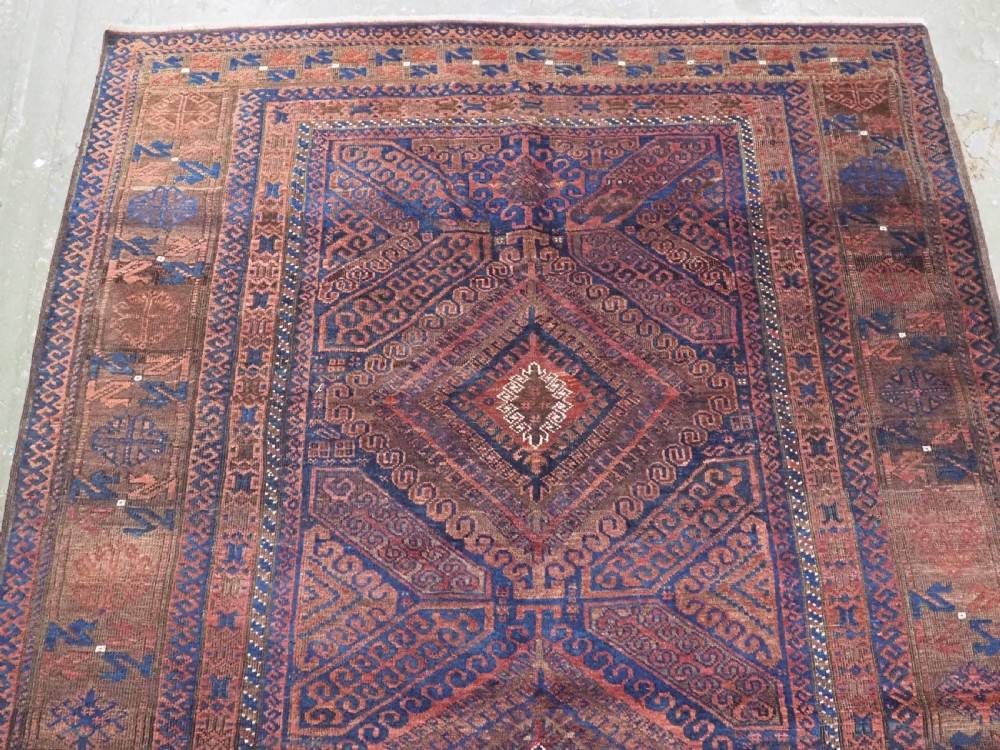 An antique hand-knotted wool carpet featuring dark brown and indigo geometric diamond medallions and detailed decorative borders. View III
