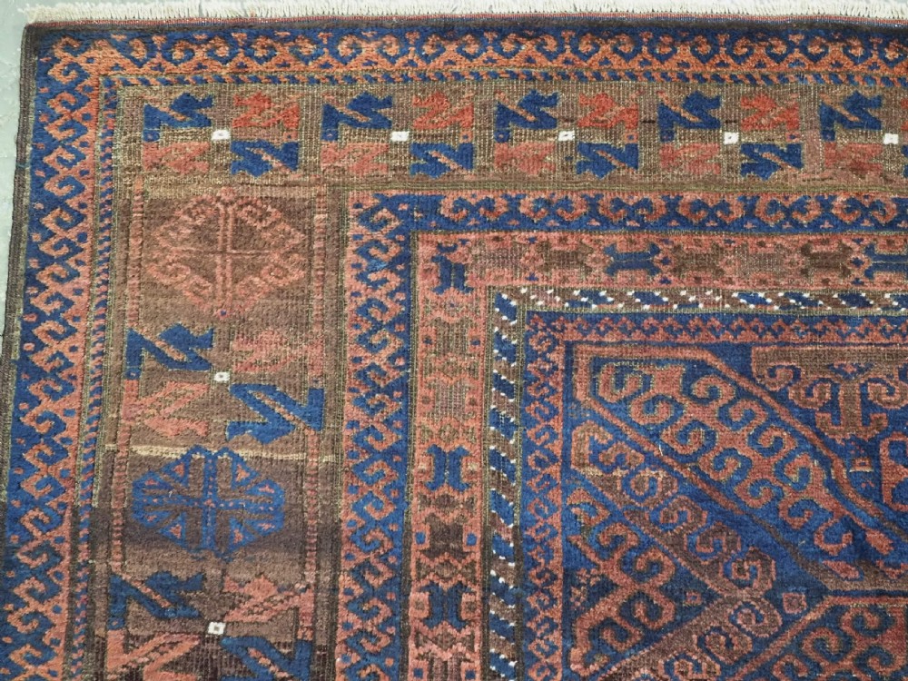 An antique hand-knotted wool carpet featuring dark brown and indigo geometric diamond medallions and detailed decorative borders. View VI