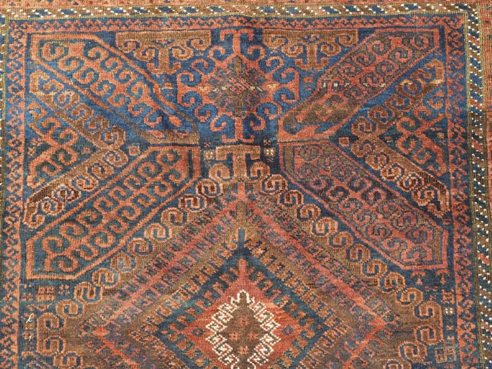 An antique hand-knotted wool carpet featuring dark brown and indigo geometric diamond medallions and detailed decorative borders. View VIII