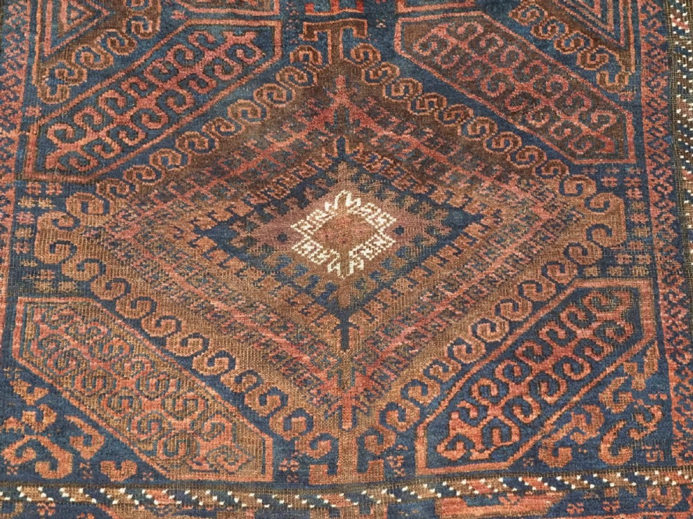 An antique hand-knotted wool carpet featuring dark brown and indigo geometric diamond medallions and detailed decorative borders. View XI