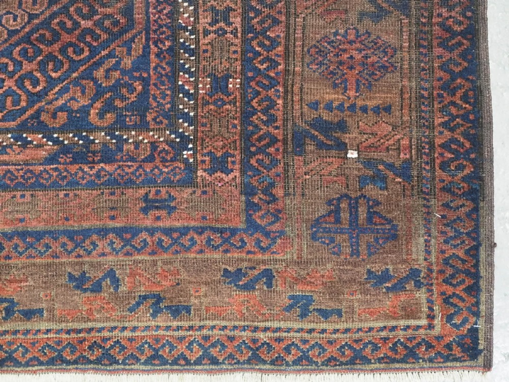 An antique hand-knotted wool carpet featuring dark brown and indigo geometric diamond medallions and detailed decorative borders. View XII