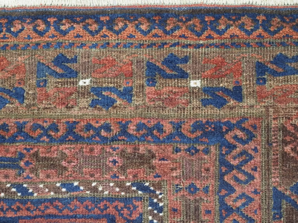 An antique hand-knotted wool carpet featuring dark brown and indigo geometric diamond medallions and detailed decorative borders. View XIII