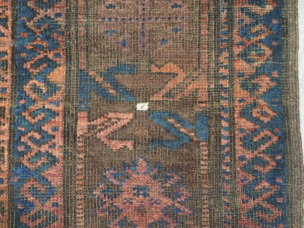 An antique hand-knotted wool carpet featuring dark brown and indigo geometric diamond medallions and detailed decorative borders. View XV