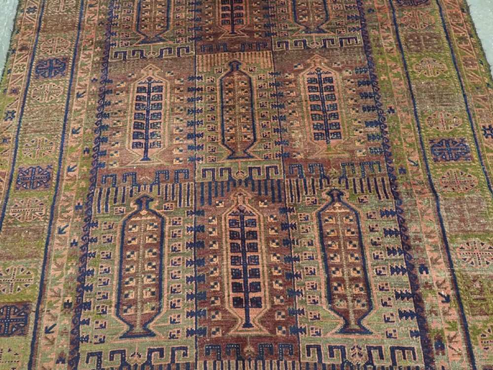 An antique hand-knotted Timuri Baluch wool carpet featuring geometric tree motifs in terracotta, indigo, and olive green hues with woven kilim borders. View III