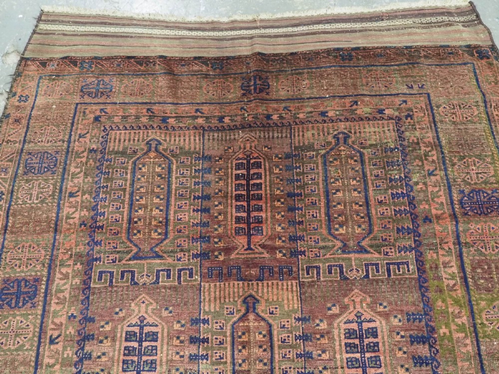 An antique hand-knotted Timuri Baluch wool carpet featuring geometric tree motifs in terracotta, indigo, and olive green hues with woven kilim borders. View IV
