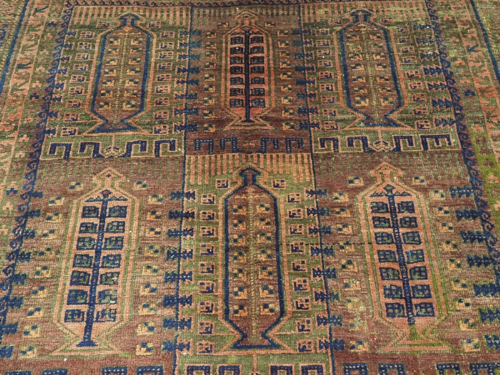 An antique hand-knotted Timuri Baluch wool carpet featuring geometric tree motifs in terracotta, indigo, and olive green hues with woven kilim borders. View VIII