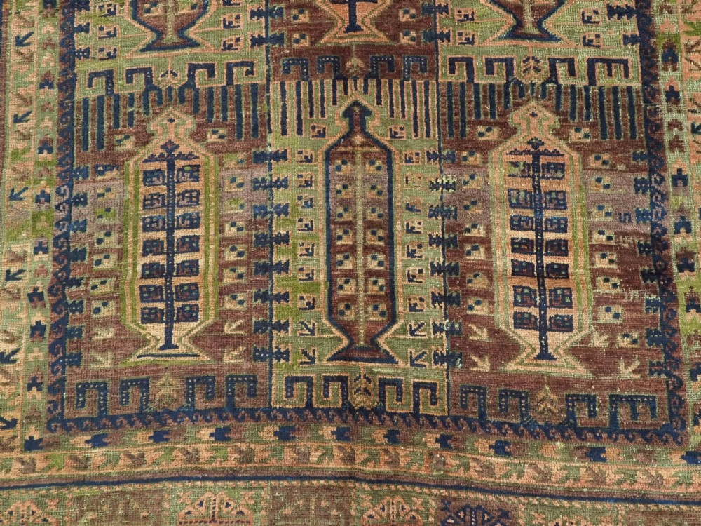 An antique hand-knotted Timuri Baluch wool carpet featuring geometric tree motifs in terracotta, indigo, and olive green hues with woven kilim borders. View X