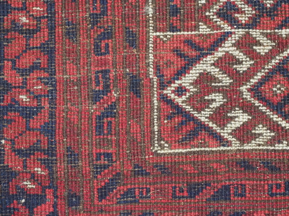 A rectangular hand-knotted wool carpet featuring a deep red field decorated with two columns of octagonal gul motifs surrounded by geometric borders. View XIV