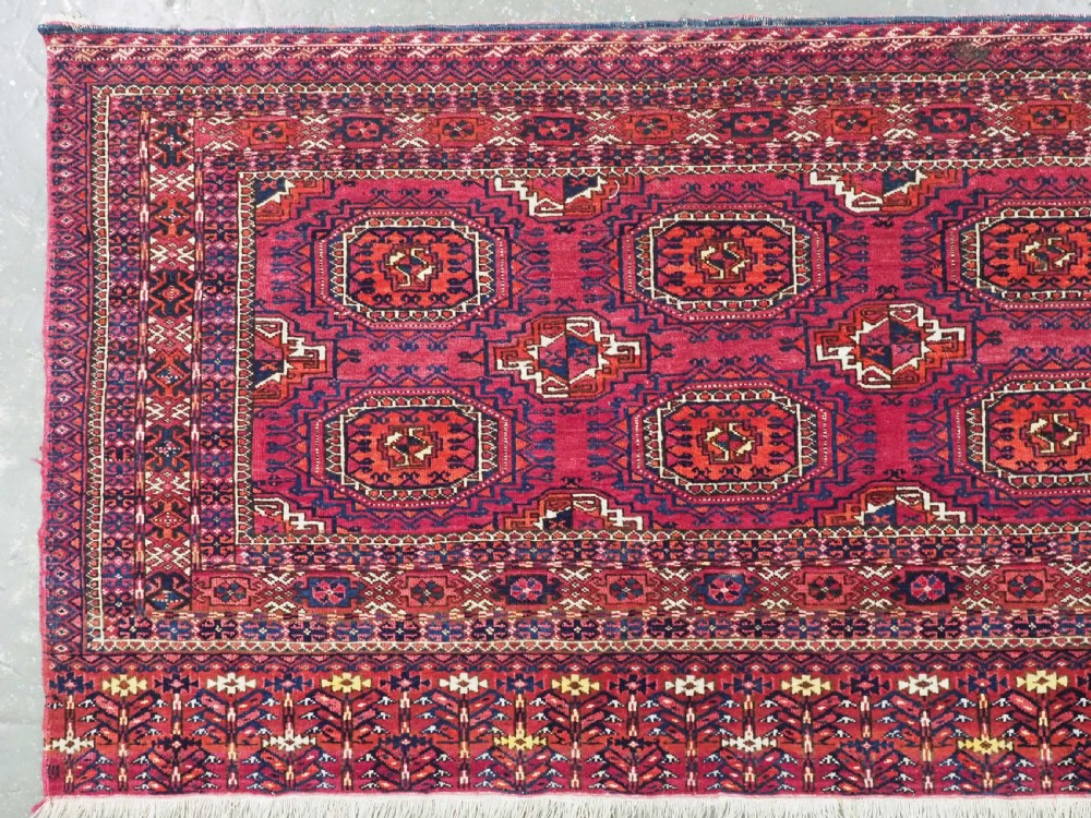 A hand-knotted crimson wool Tekke Turkmen chuval face featuring six octagonal Salor guls and geometric borders with fringe detailing. View II
