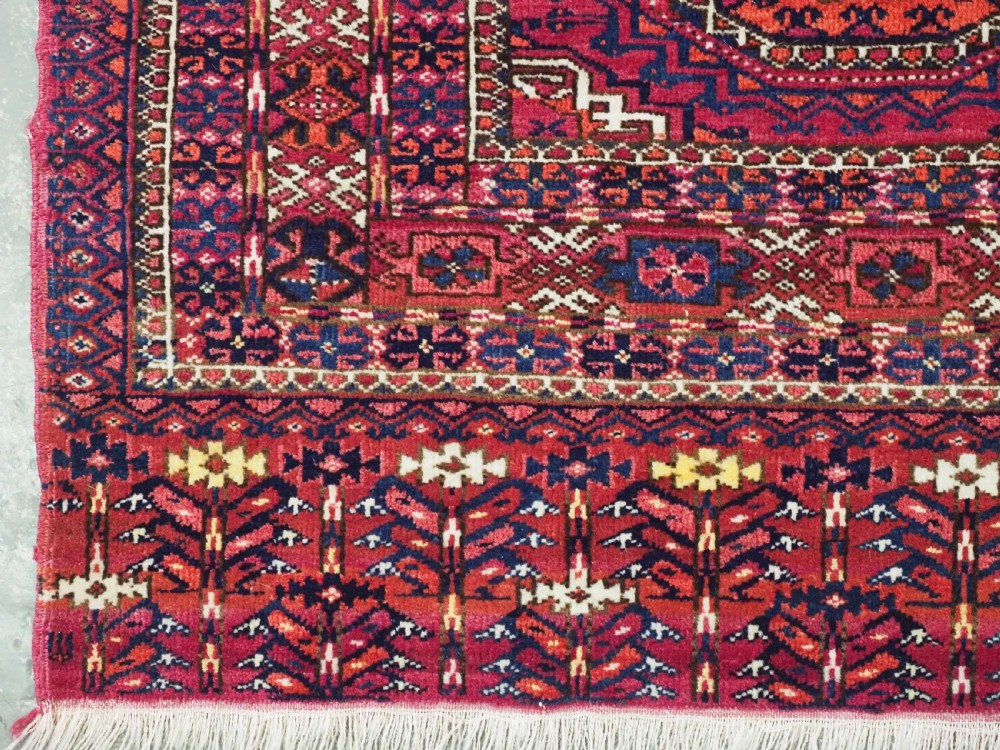 A hand-knotted crimson wool Tekke Turkmen chuval face featuring six octagonal Salor guls and geometric borders with fringe detailing. View IV