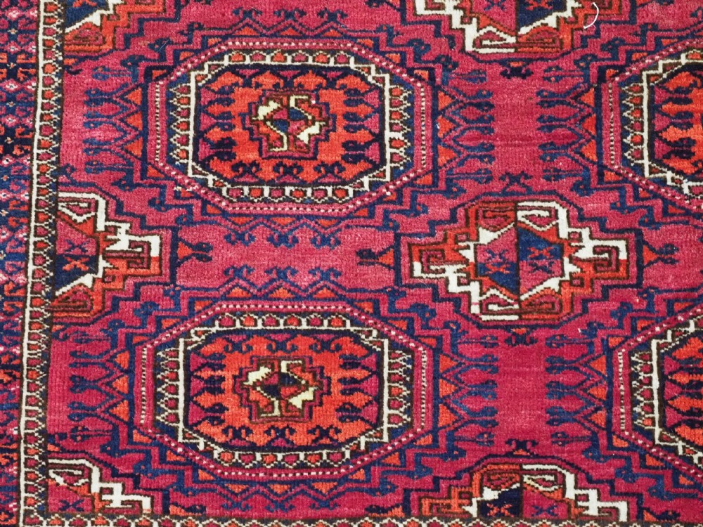 A hand-knotted crimson wool Tekke Turkmen chuval face featuring six octagonal Salor guls and geometric borders with fringe detailing. View V