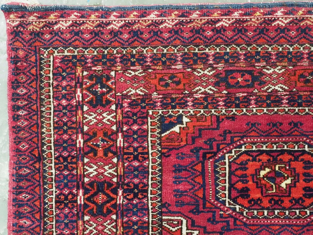A hand-knotted crimson wool Tekke Turkmen chuval face featuring six octagonal Salor guls and geometric borders with fringe detailing. View VII