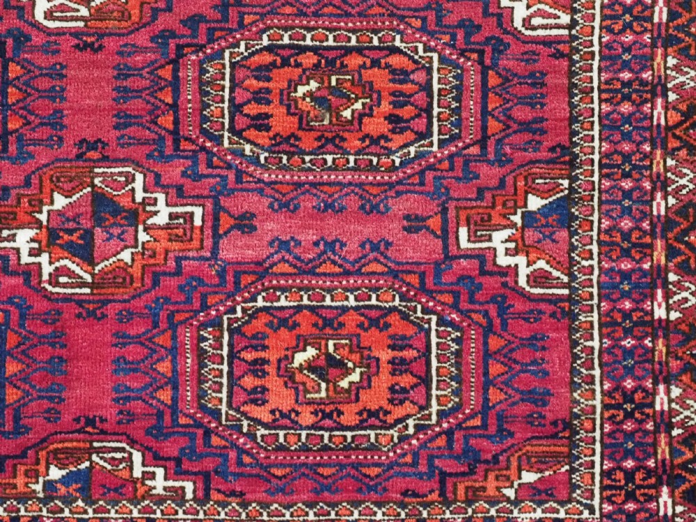 A hand-knotted crimson wool Tekke Turkmen chuval face featuring six octagonal Salor guls and geometric borders with fringe detailing. View IX