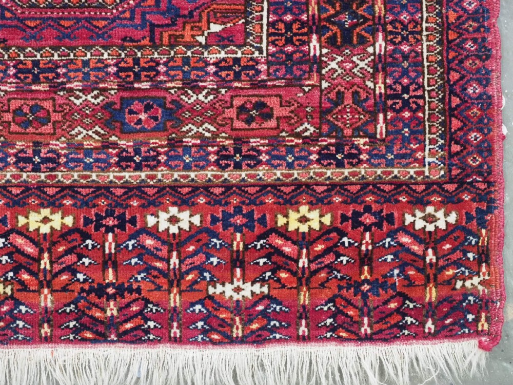 A hand-knotted crimson wool Tekke Turkmen chuval face featuring six octagonal Salor guls and geometric borders with fringe detailing. View XI