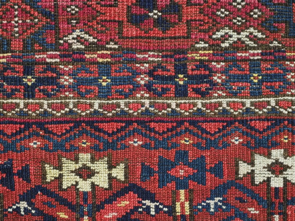 A hand-knotted crimson wool Tekke Turkmen chuval face featuring six octagonal Salor guls and geometric borders with fringe detailing. View XII