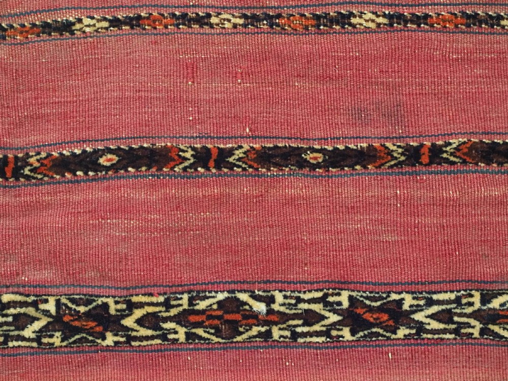 A horizontal rectangular antique Tekke Turkmen Kizil chuval face textile woven in red wool with dark geometric striped bands. View VI