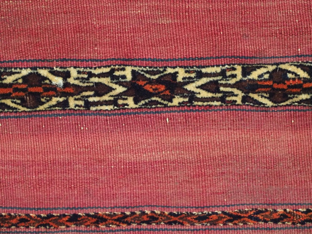 A horizontal rectangular antique Tekke Turkmen Kizil chuval face textile woven in red wool with dark geometric striped bands. View VII