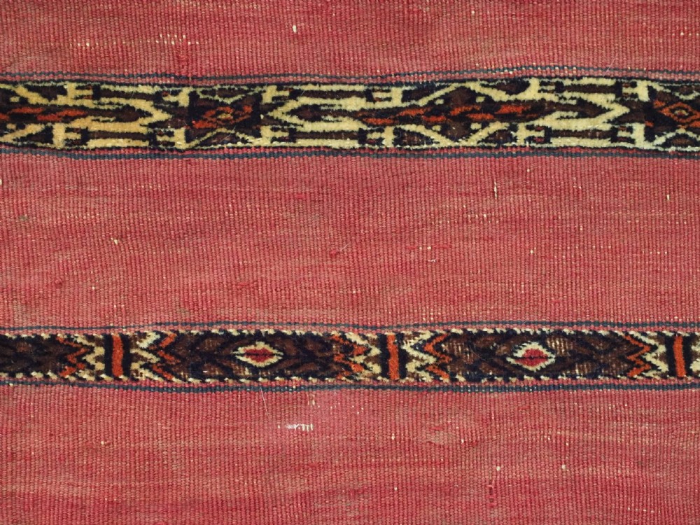 A horizontal rectangular antique Tekke Turkmen Kizil chuval face textile woven in red wool with dark geometric striped bands. View VIII