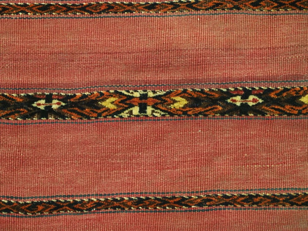 A horizontal rectangular antique Tekke Turkmen Kizil chuval face textile woven in red wool with dark geometric striped bands. View X