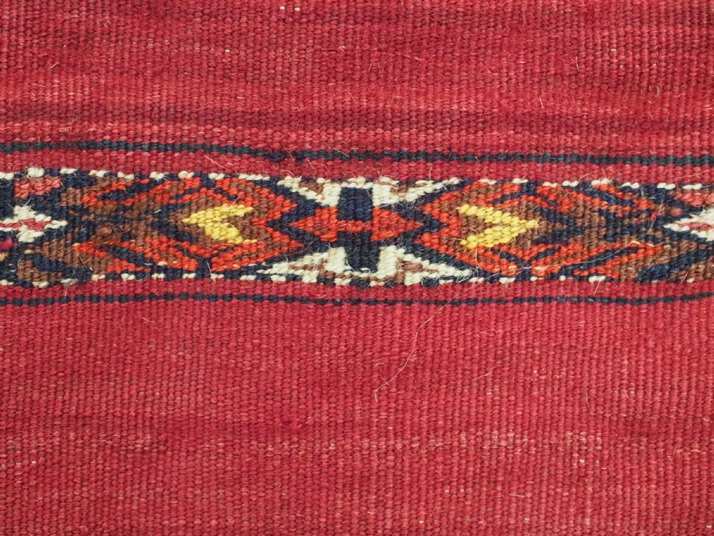 A horizontal rectangular antique Tekke Turkmen Kizil chuval face textile woven in red wool with dark geometric striped bands. View XI