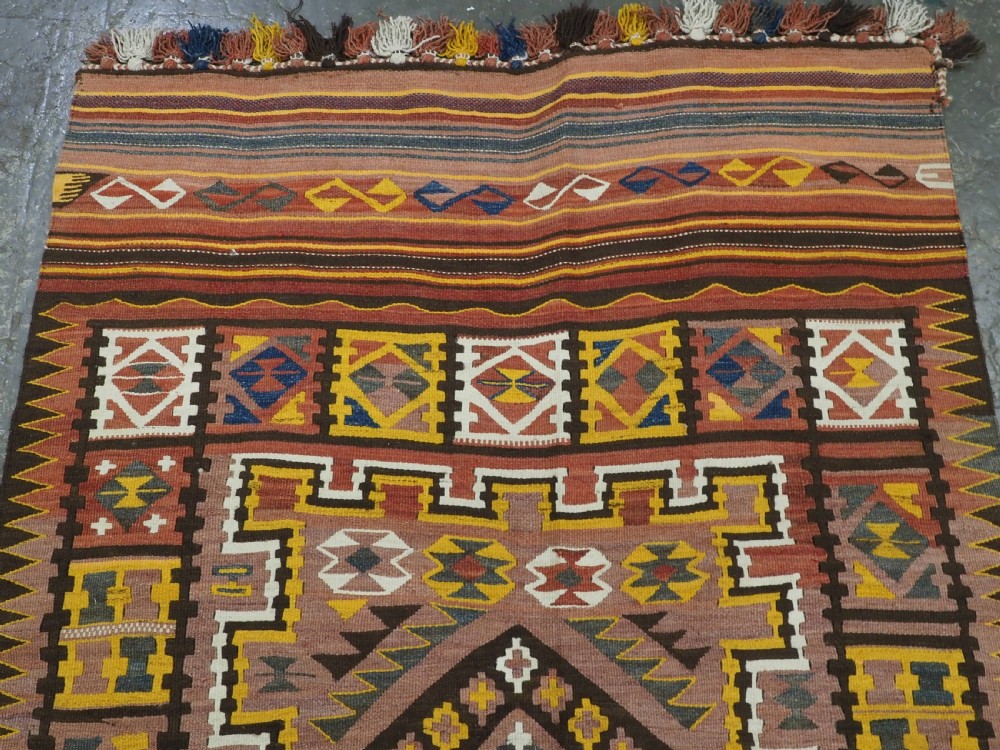 A long flat-woven Afghan kilim runner carpet featuring geometric diamond motifs in terracotta, brown, yellow, and ivory shades with a tasseled fringe. View III