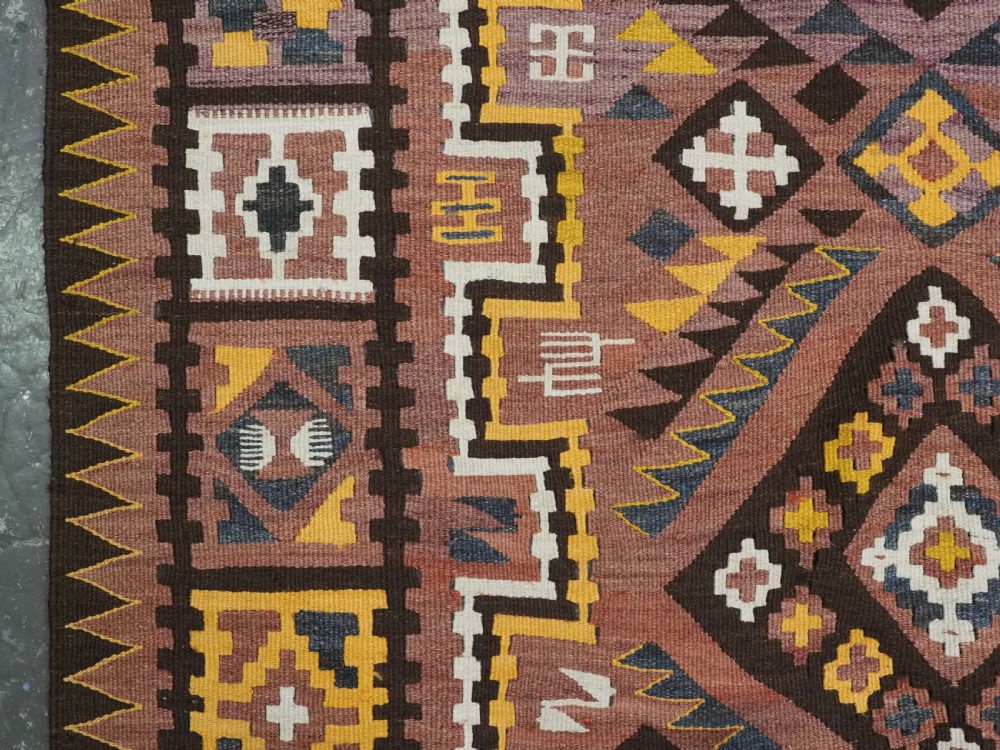 A long flat-woven Afghan kilim runner carpet featuring geometric diamond motifs in terracotta, brown, yellow, and ivory shades with a tasseled fringe. View VIII