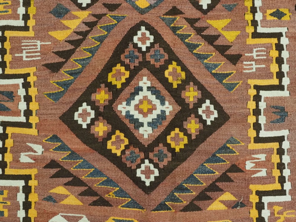 A long flat-woven Afghan kilim runner carpet featuring geometric diamond motifs in terracotta, brown, yellow, and ivory shades with a tasseled fringe. View XI