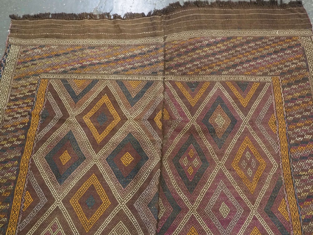 An antique Afghan flatweave wool kilim rug featuring a central brown field filled with geometric diamond motifs framed by patterned borders. View III
