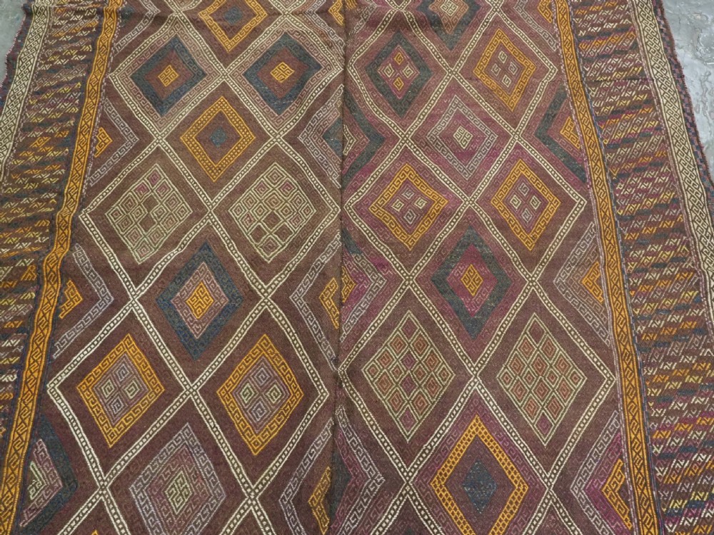 An antique Afghan flatweave wool kilim rug featuring a central brown field filled with geometric diamond motifs framed by patterned borders. View IV
