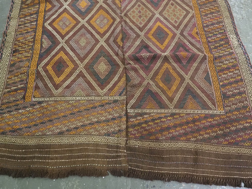 An antique Afghan flatweave wool kilim rug featuring a central brown field filled with geometric diamond motifs framed by patterned borders. View V