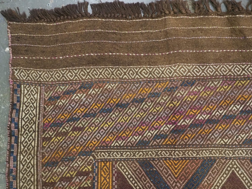 An antique Afghan flatweave wool kilim rug featuring a central brown field filled with geometric diamond motifs framed by patterned borders. View VI