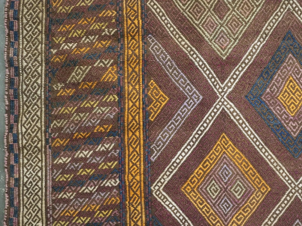 An antique Afghan flatweave wool kilim rug featuring a central brown field filled with geometric diamond motifs framed by patterned borders. View VII