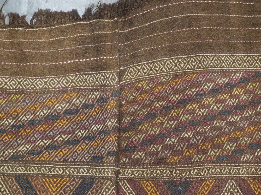 An antique Afghan flatweave wool kilim rug featuring a central brown field filled with geometric diamond motifs framed by patterned borders. View VIII